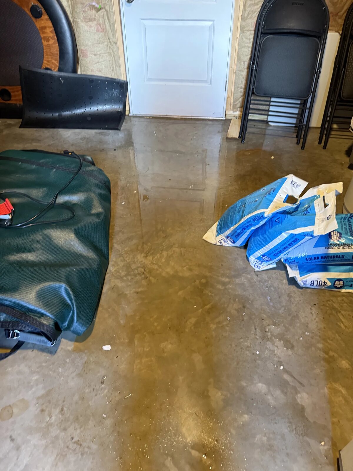 Standing water covering the finished basement floor near the exterior door, before mitigation work began.